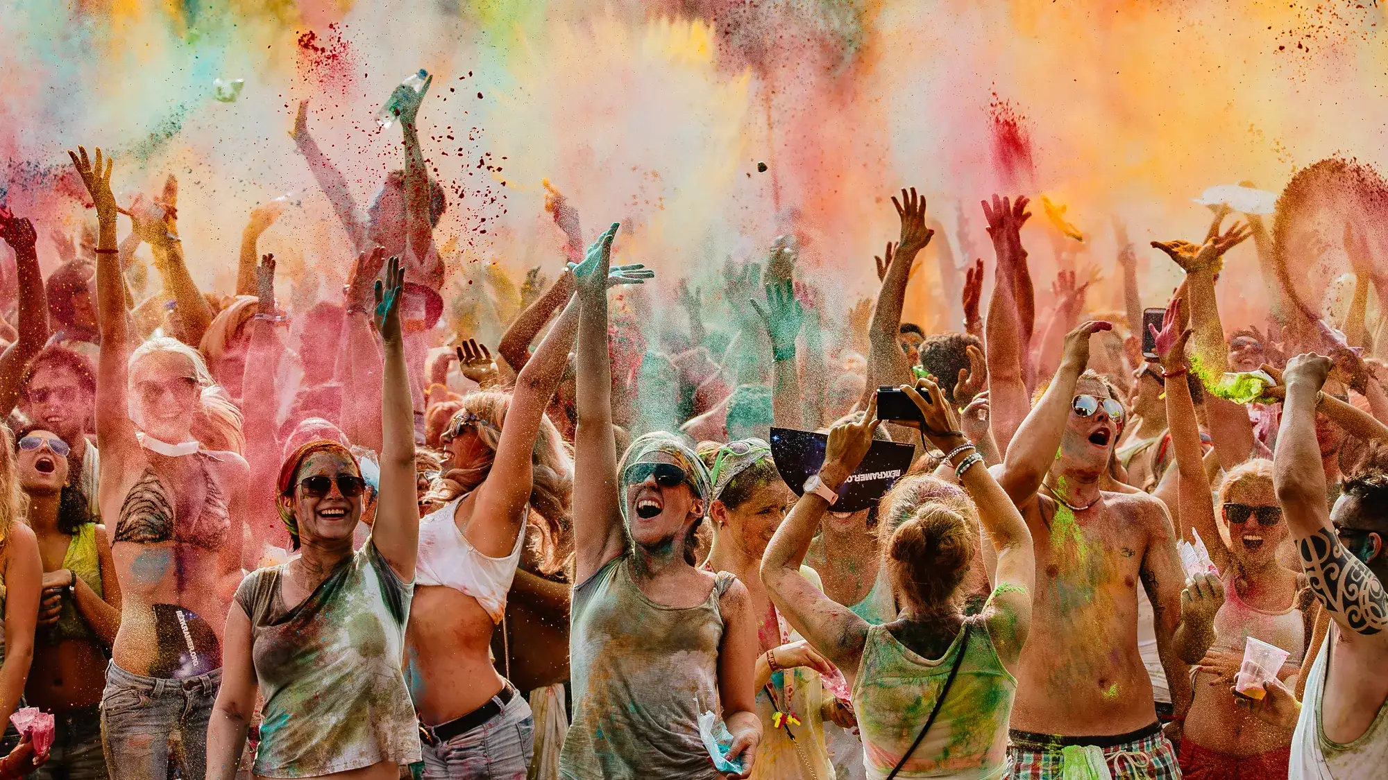 Menschen feiern beim Holi Festival und werfen bunte Farbe in die Luft
