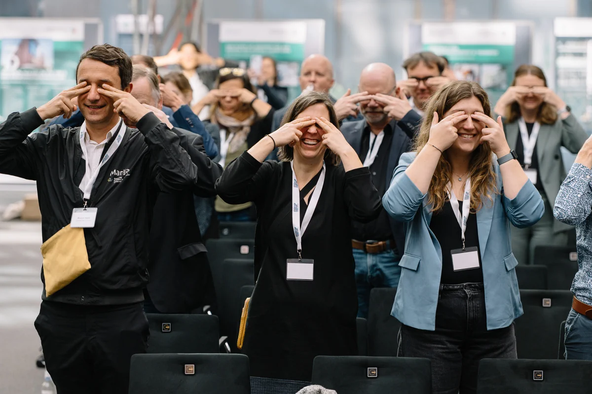 Publikum hält sich während einer Keynote die Augen zu und lacht.