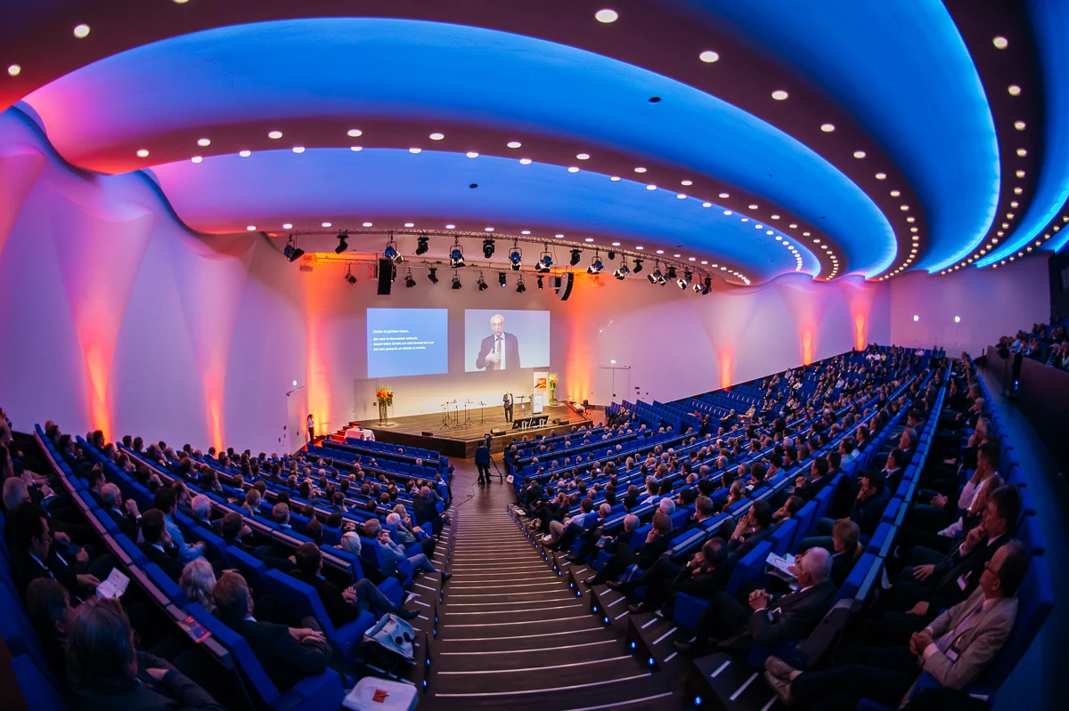 Blick über das volle Auditorium zur Bühne während eines Events.