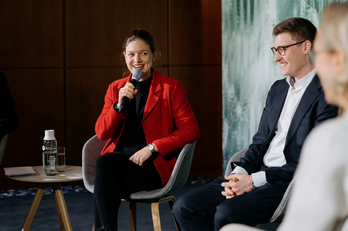 Frau spricht in einer Talkrunde gemeinsam mit weiteren Teilnehmern.