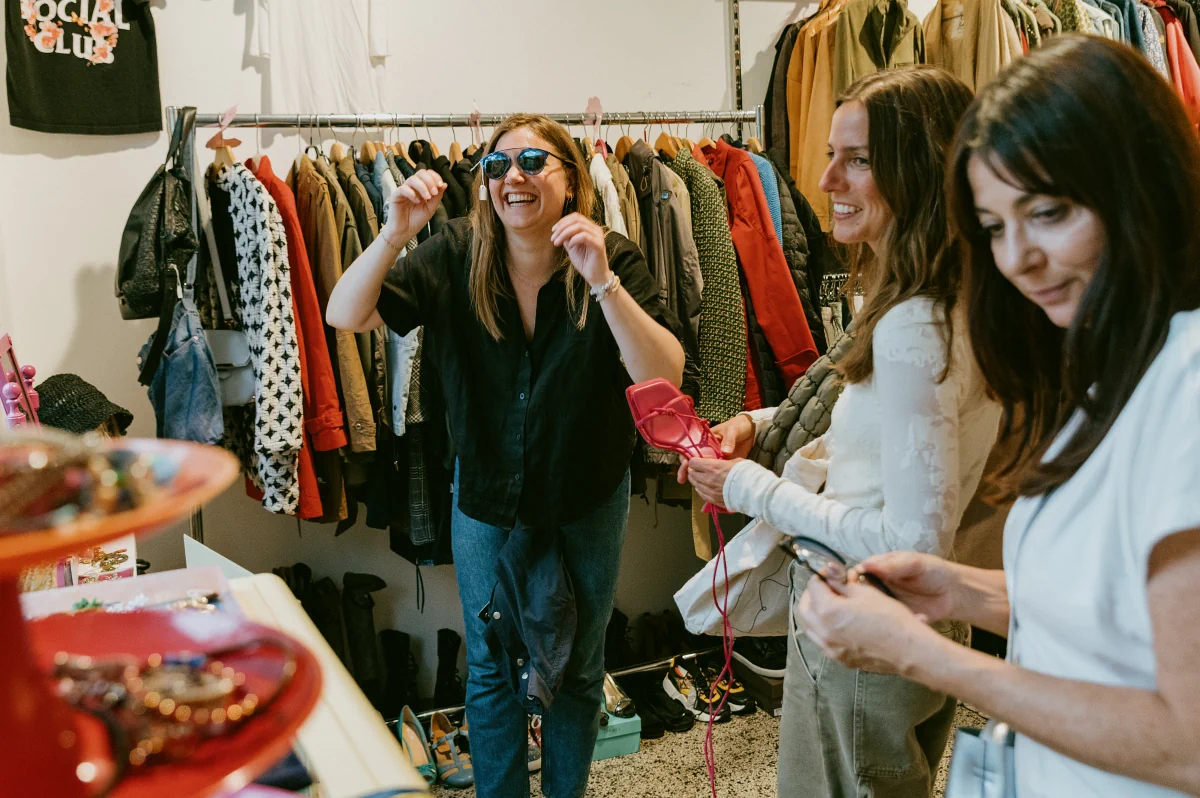 Frau probiert Sonnenbrille im Laden, sie und ihre Freundin lachen.